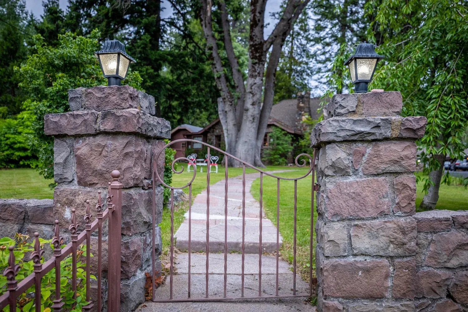 A wrought-iron garden gate between stone pillars